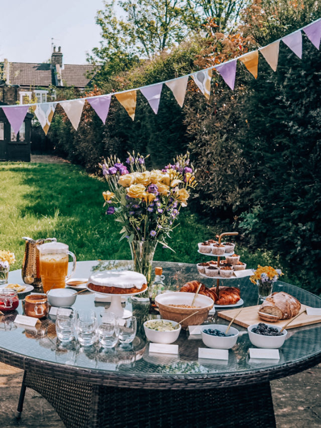 Various food and drink items and flowers in a vase on a table to hosting a brunch party.