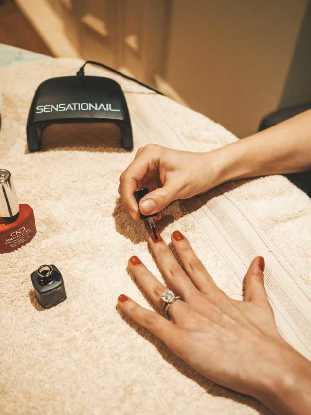 Woman painting her nails red during a shellac manicure at home.