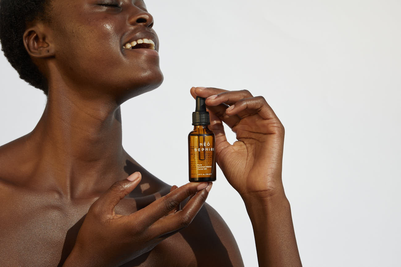 Smiling model holding Nêô Sephiri Kalahari Melon Oil