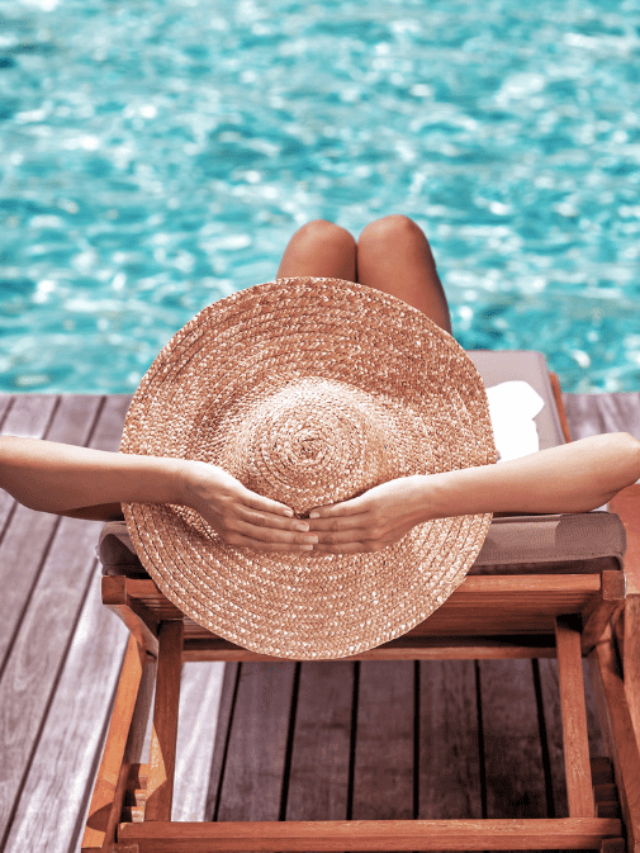 Woman relaxing by a pool wearing a sunhat and living luxuriously