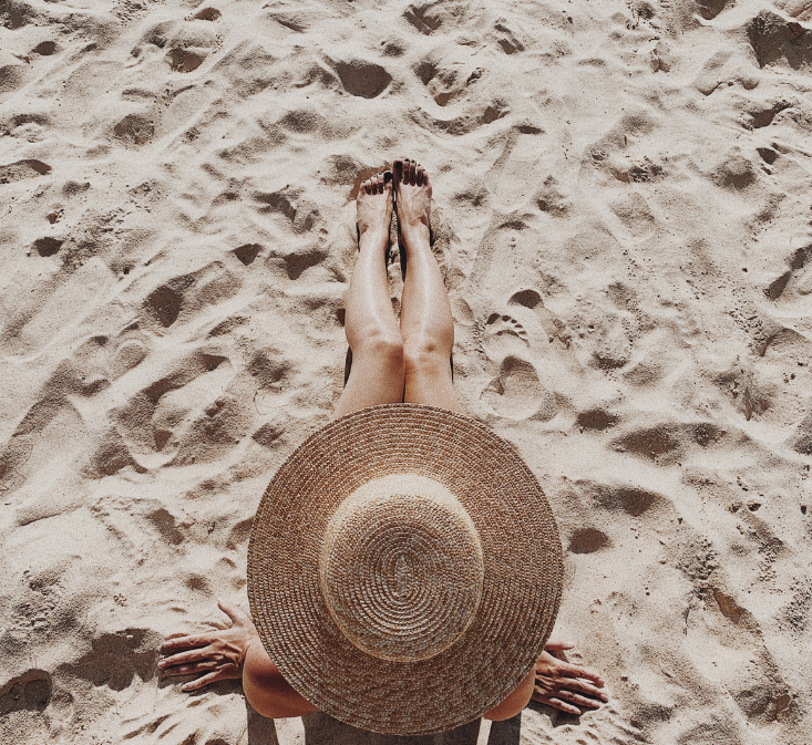 Woman wearing a sunhat in the sand, shot from above