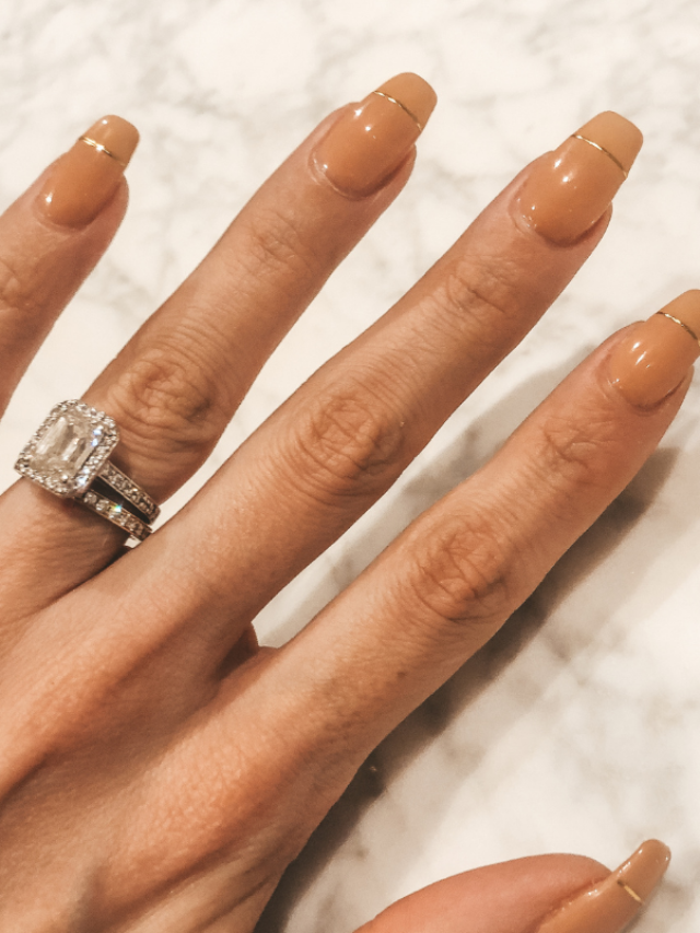 Nude nails with gold line detail against a marble background