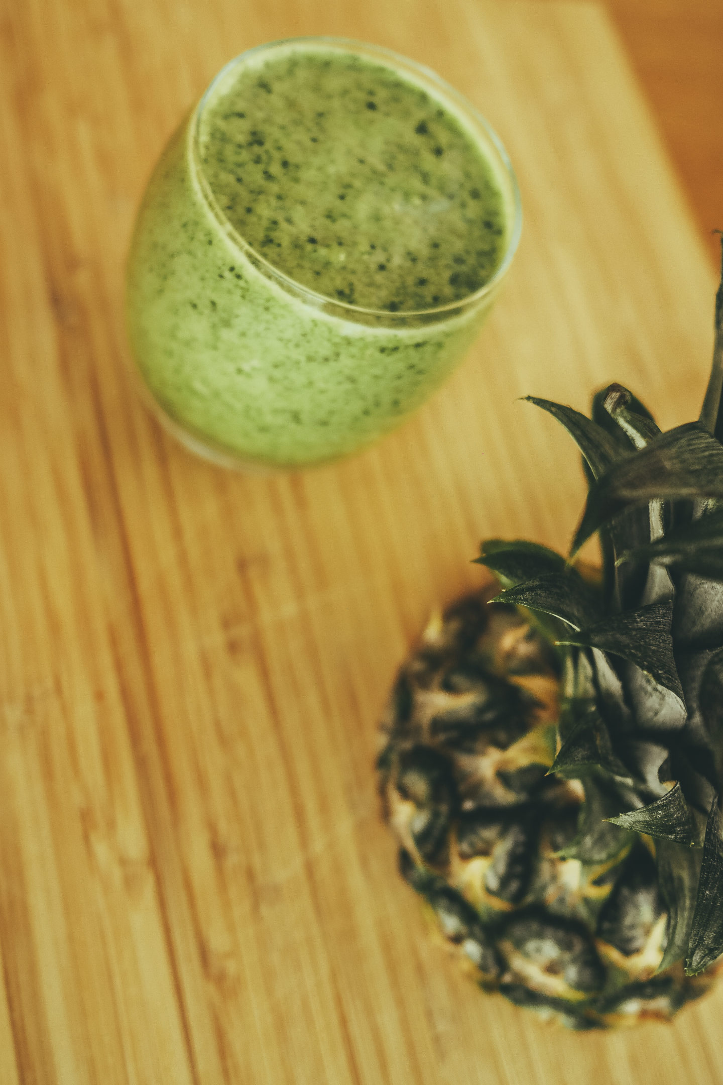 Apple spinach smoothie and pineapple board on wooden chopping board