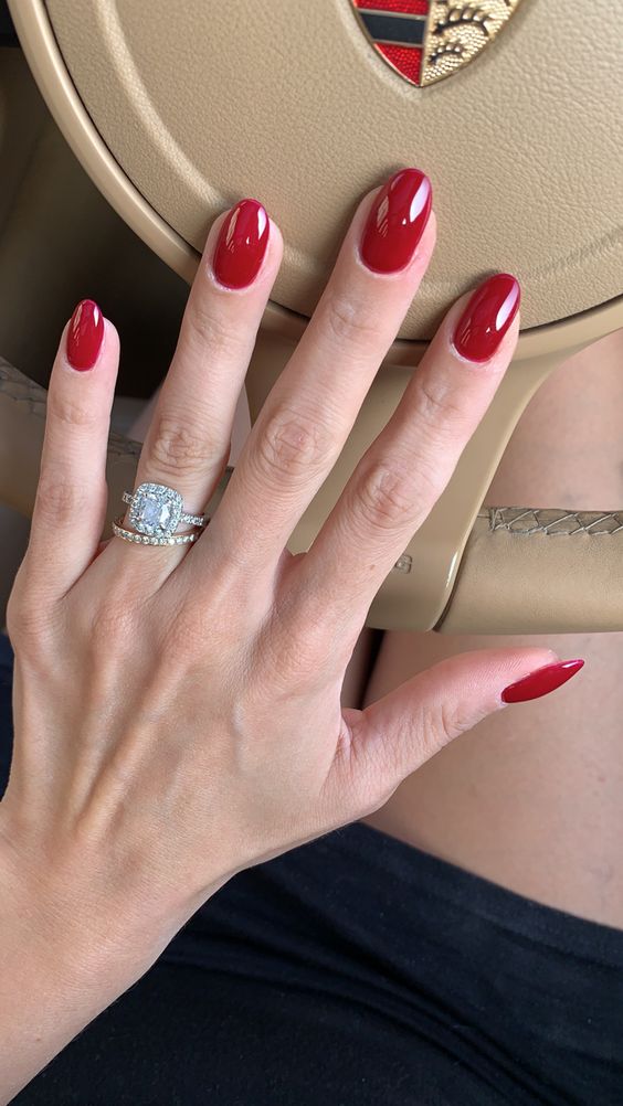 Classic red nails against a beige steering wheel