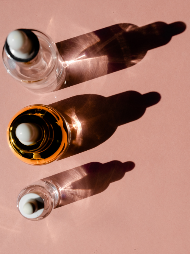 3 serum bottle of retinol and retinoid on a pink surface