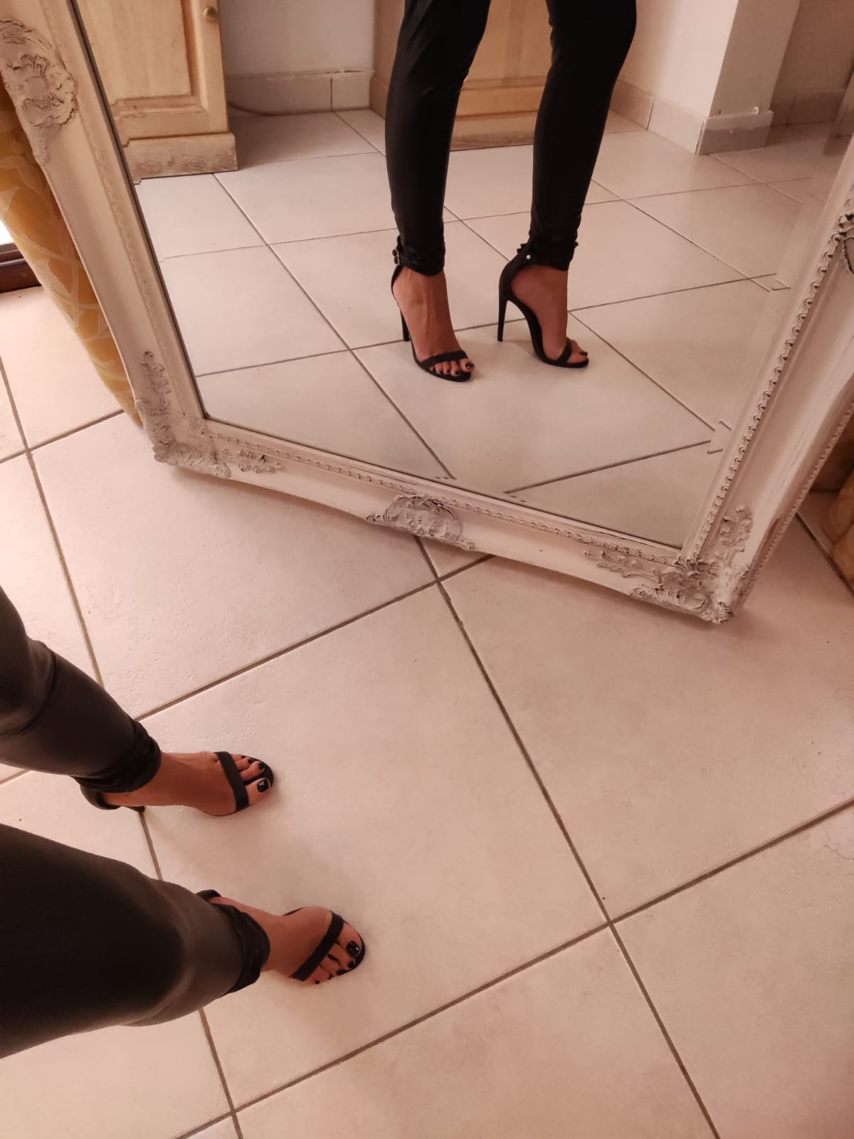 Black leather leggings and strappy sandals in a mirror