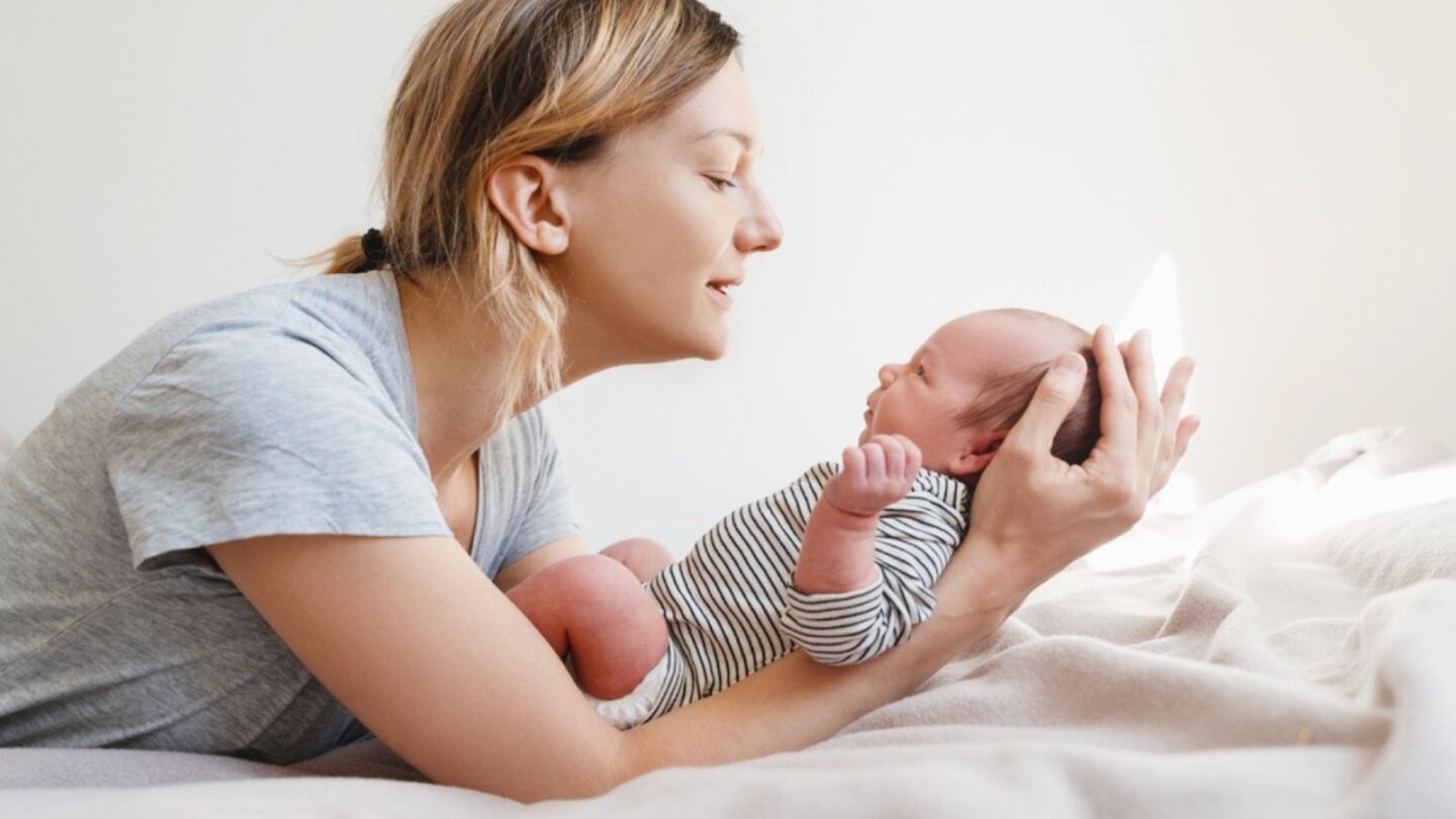 Loving mom spending time with her little 2 week old child at home