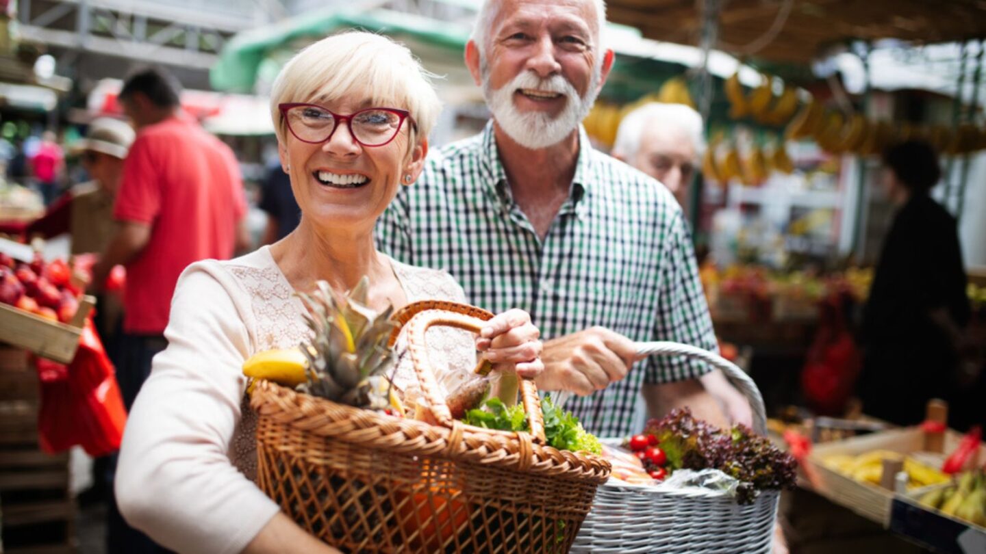 Mature couple shopping vegetables and fruits on the market.