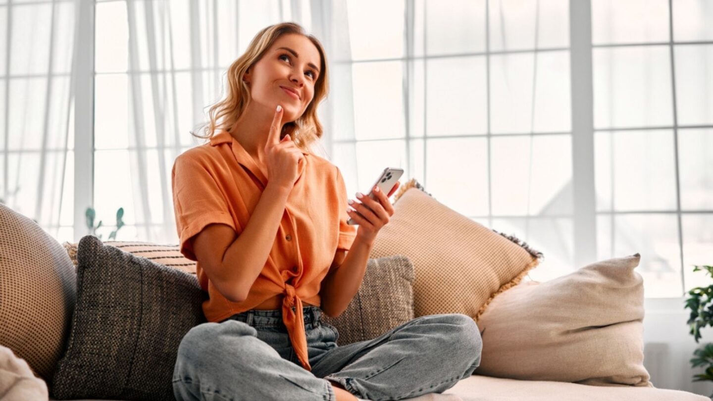 Pensive woman dressed in casual clothes using modern smartphone