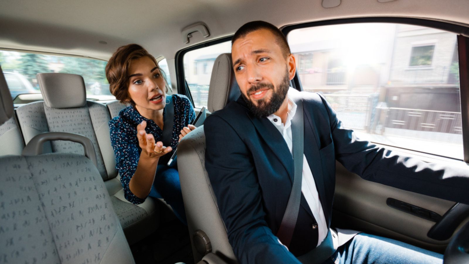 Taxi driver driving a car and having an argument with female passenger.