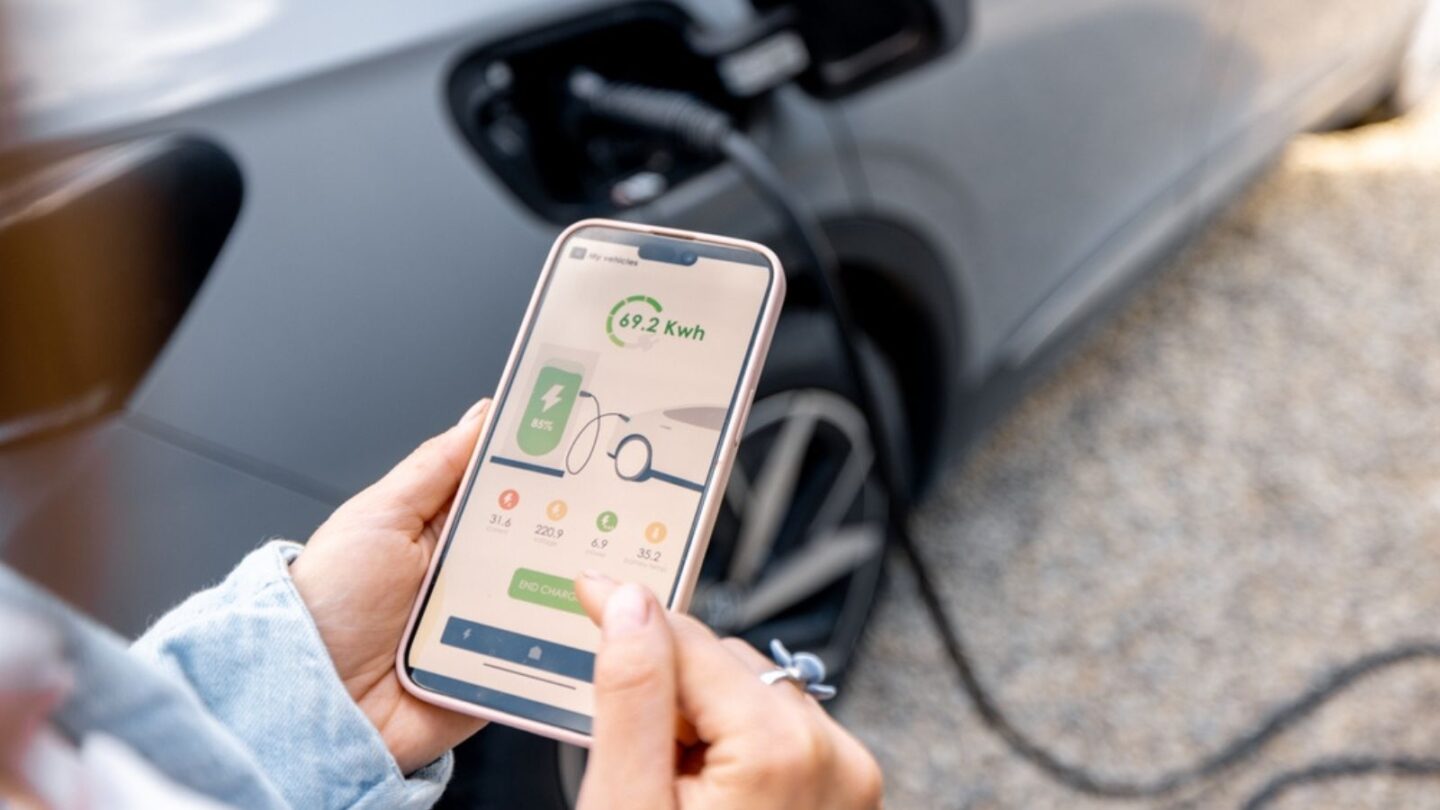 Woman using smartphone with launched application for car charging