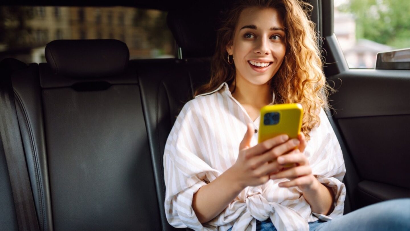 Woman with seat belt using phone inside car.