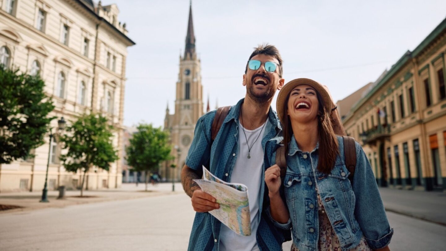 Young couple of travelers laughing and having fun while walking in the city