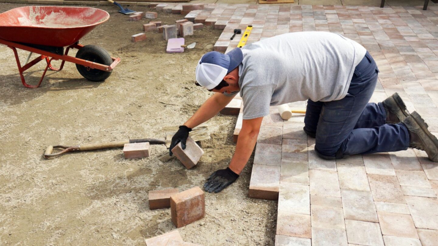 Young man paving or laying down pavers as part of landscaping