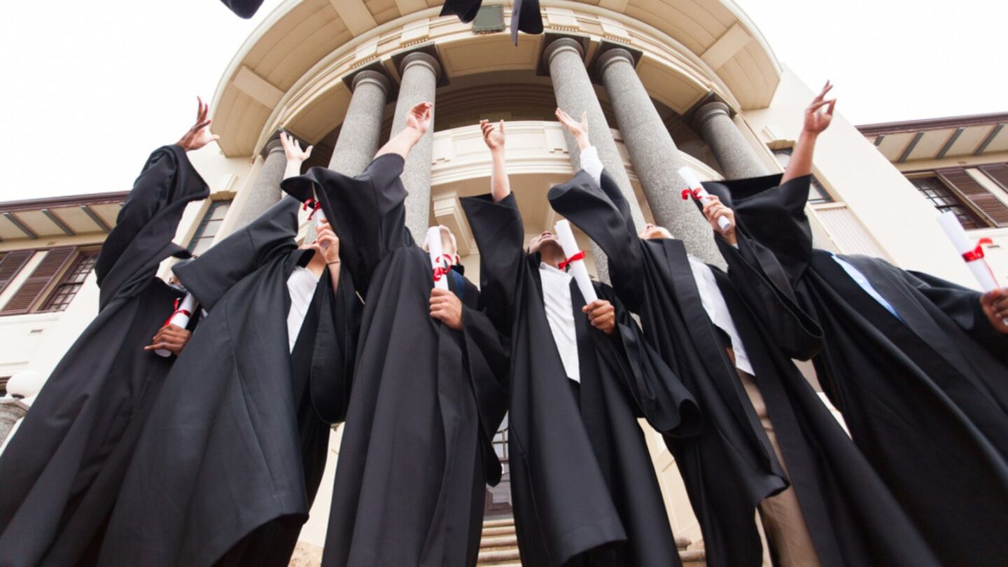 graduates throw graduation hats in the air in celebration