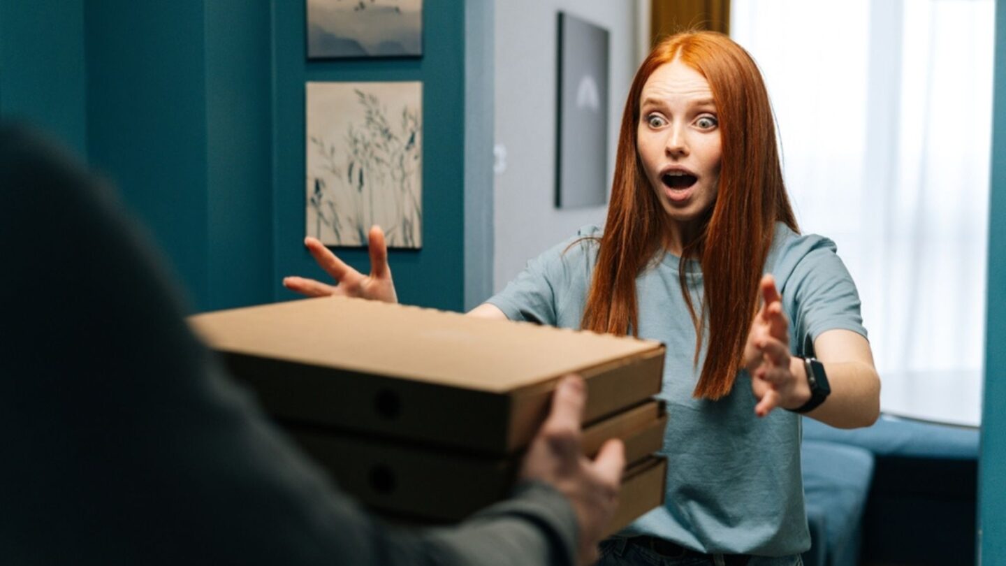 woman receiving paper boxes with hot pizza from unrecognizable courier